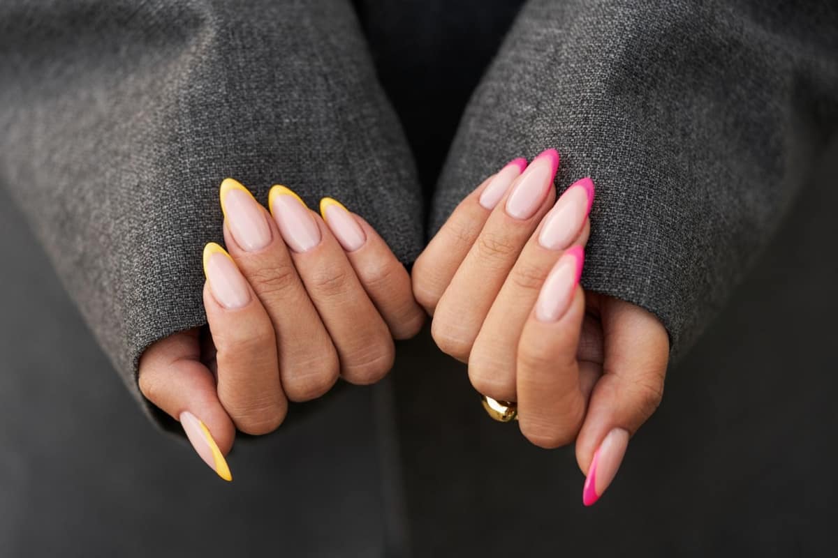 Main aux ongles courts corail avec micro-french sur une terrasse estivale