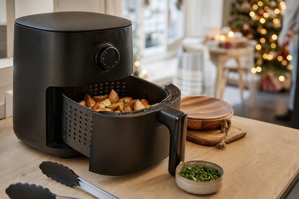 Airfryer ouvert avec pommes de terre rôties sur un plan de travail de cuisine