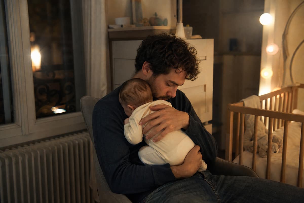 Parent berçant doucement son bébé dans une chambre faiblement éclairée la nuit