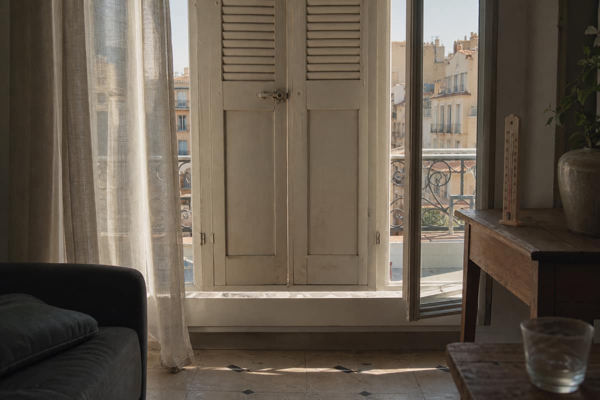 Volets extérieurs fermés devant une fenêtre ensoleillée dans un salon français