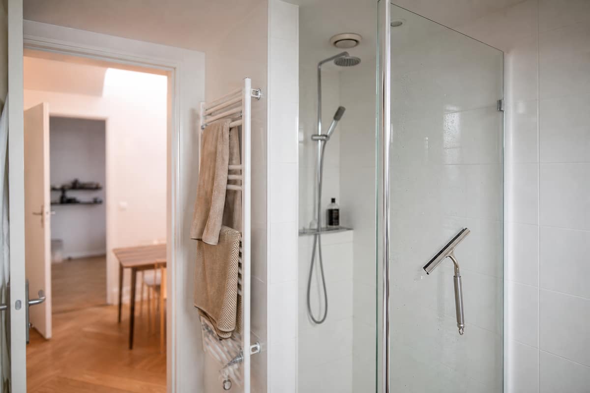 Salle de bain sans fenêtre avec raclette, bouche de VMC et sèche-serviettes