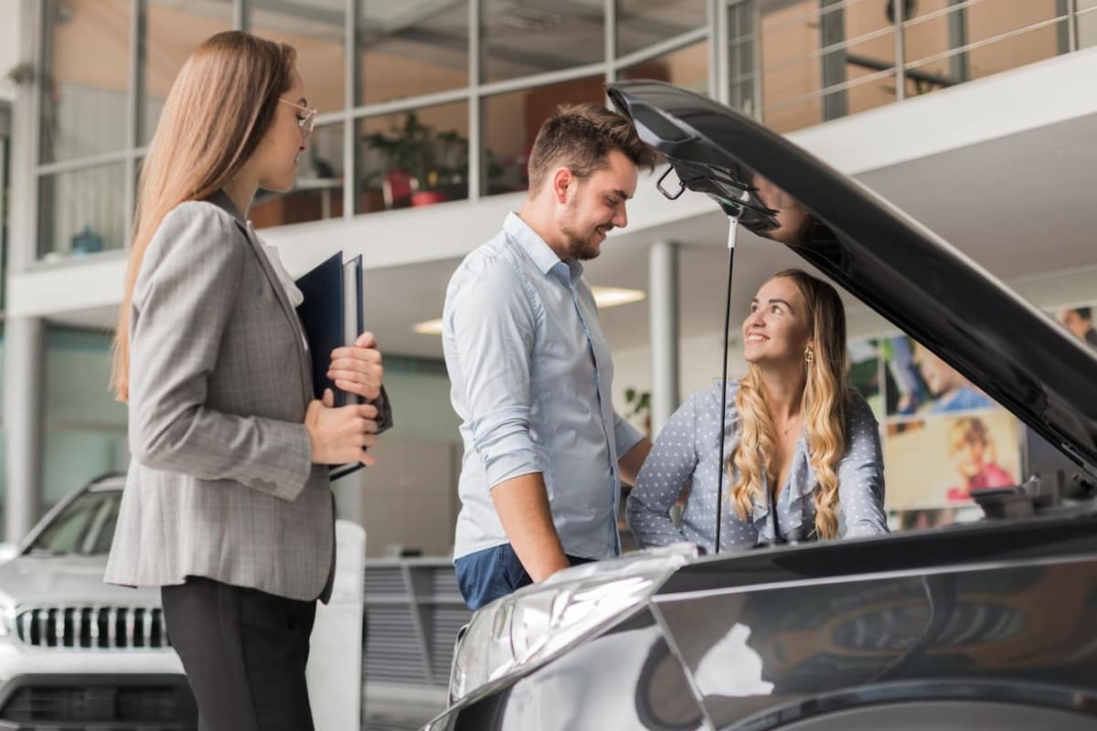 Acheteur vérifiant les documents et le moteur d’une voiture d’occasion