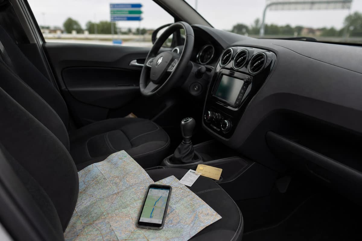 Carte routière, smartphone et ticket de péage dans une voiture familiale