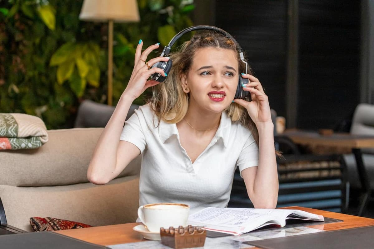 Casque audio, carnet et tasse près d’un fauteuil lumineux dans un salon calme