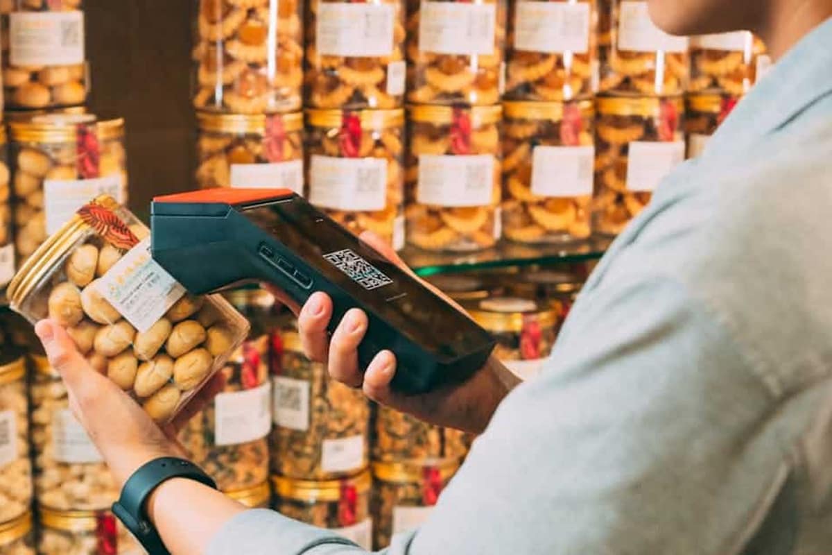 Main scannant un QR code sur un emballage en rayon de supermarché
