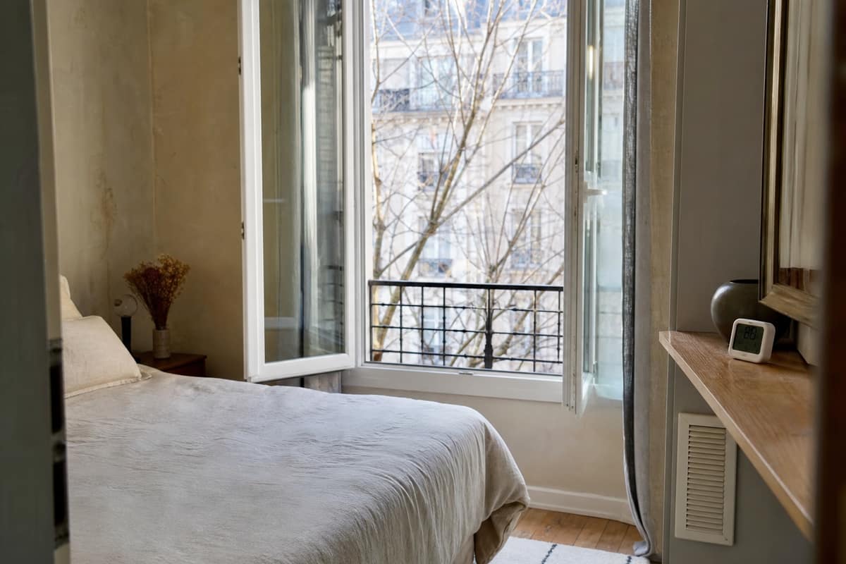 Chambre aérée avec hygromètre posé près d’une fenêtre et grille de ventilation