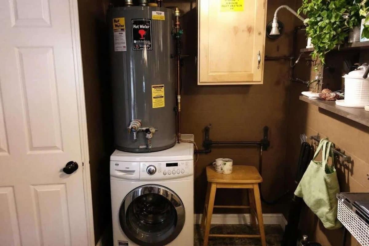 Chauffe-eau électrique vertical avec tuyaux isolés dans une buanderie française