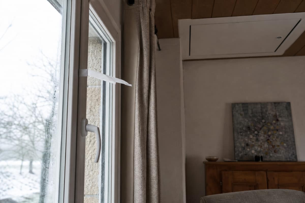 Test de courant d’air près du joint d’une fenêtre en hiver