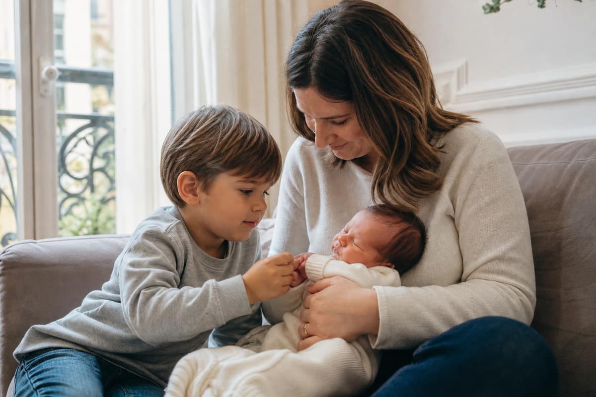 Enfant touchant délicatement la main de son petit frère nouveau-né