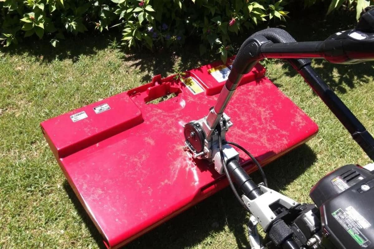 Raclette métallique étalant du sable fin sur une pelouse de jardin