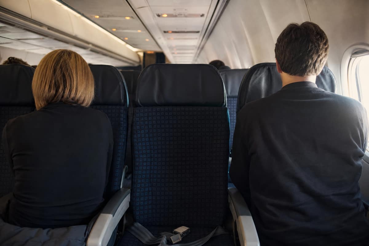 Rangée d’avion avec sièges hublot et couloir occupés, siège central libre