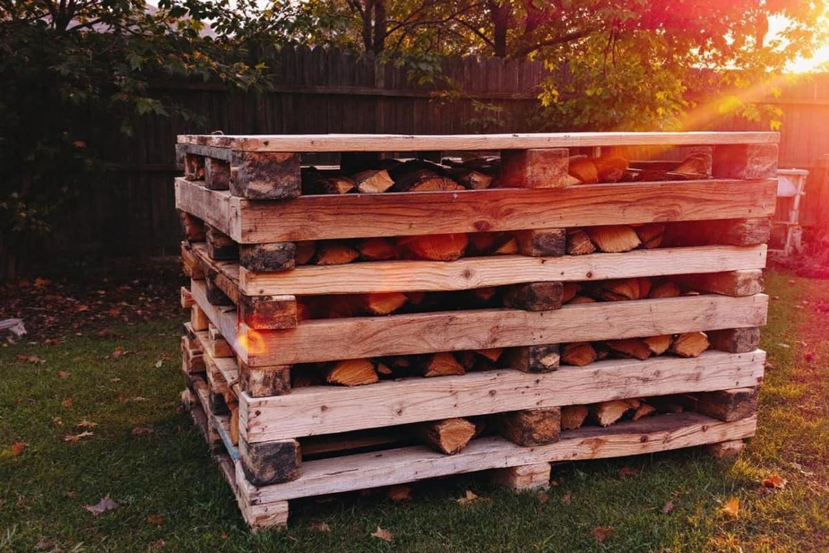 Bûches sèches près d’un poêle et palette en bois à l’arrière-plan