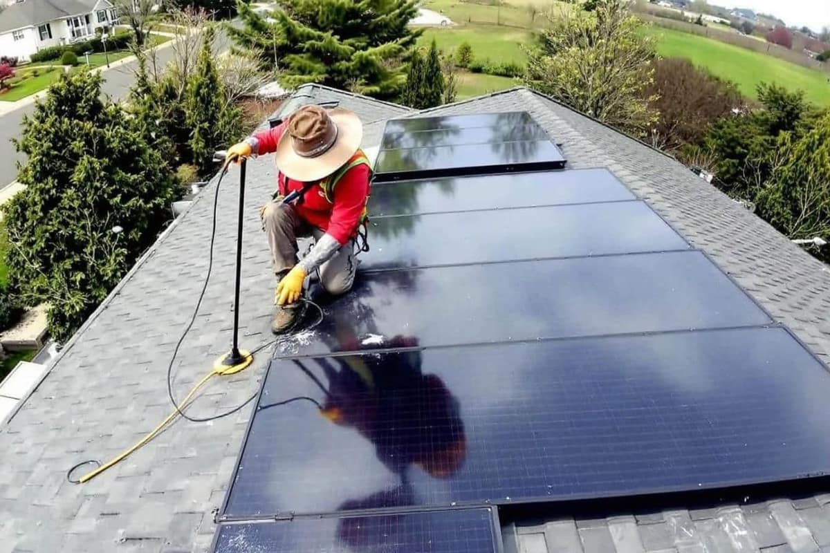 Perche à brosse douce rinçant des panneaux solaires sur une toiture résidentielle