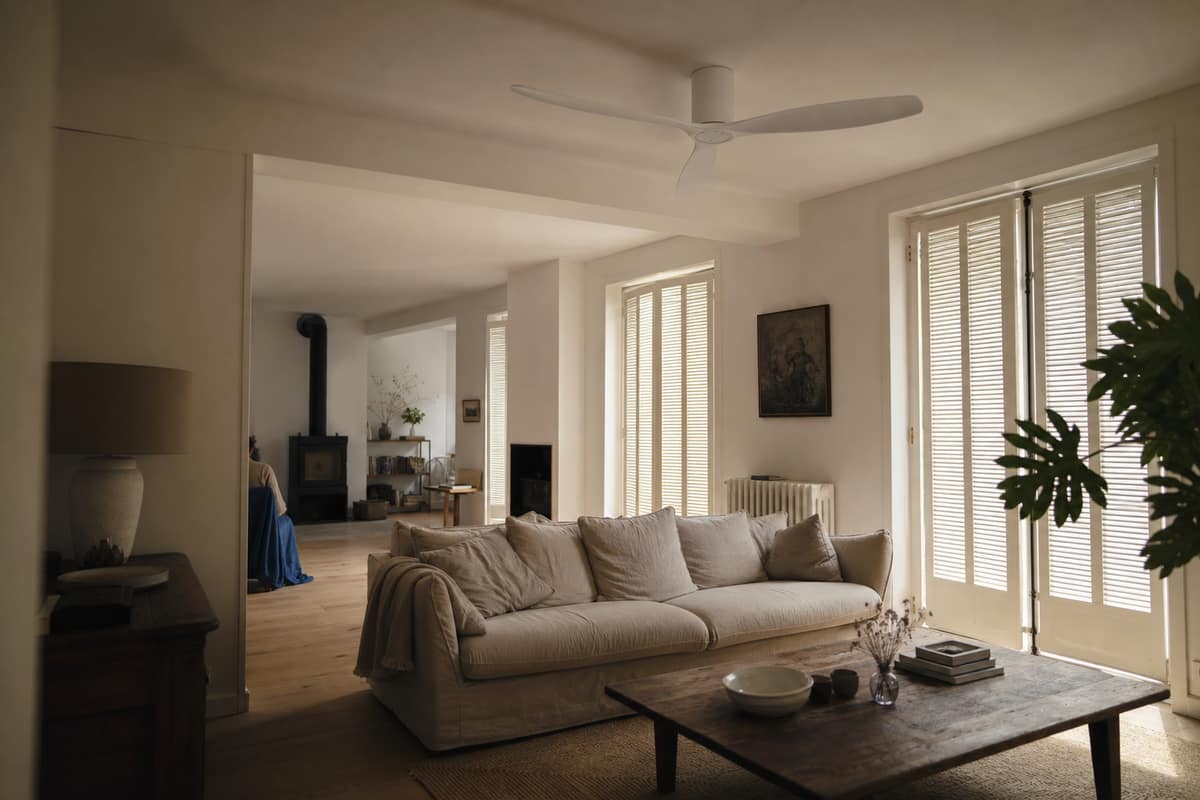 Ventilateur de plafond blanc dans un séjour lumineux avec poêle à bois