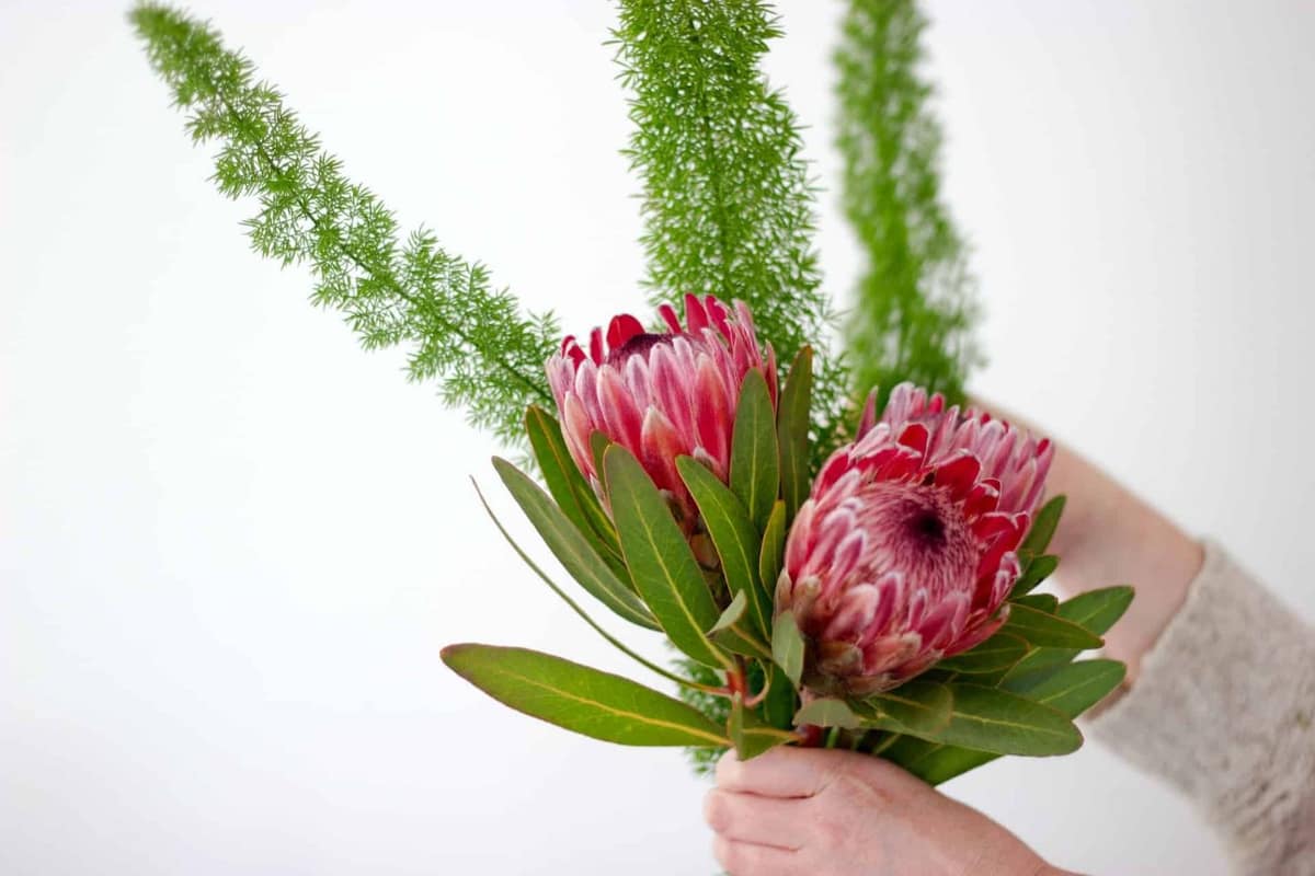 Table de mariage avec fleurs de saison, vases réemployables et plantes aromatiques