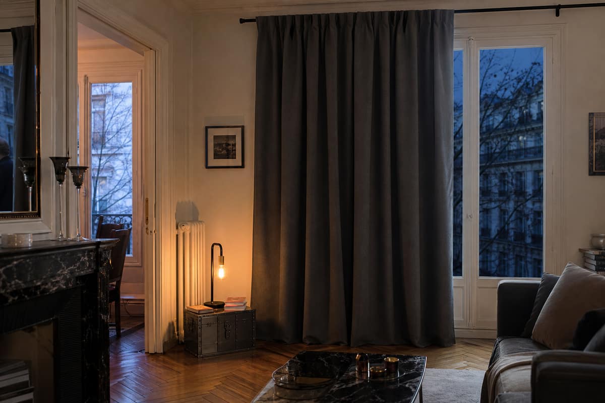 Rideau thermique épais fermé devant une grande fenêtre dans un salon lumineux