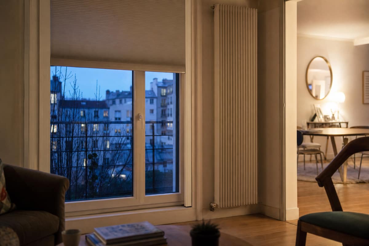 Store alvéolaire et volet roulant fermés devant une fenêtre de salon en hiver