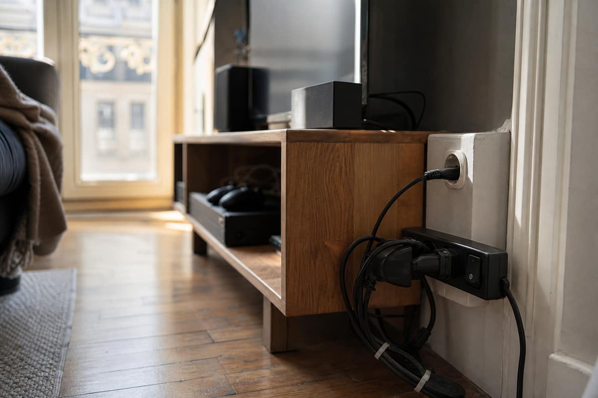 Multiprise maître-esclave branchée sous un meuble TV avec câbles organisés