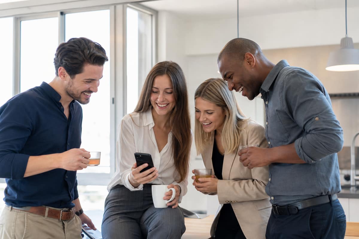 Collègues consultant ensemble un smartphone dans un espace de pause au bureau