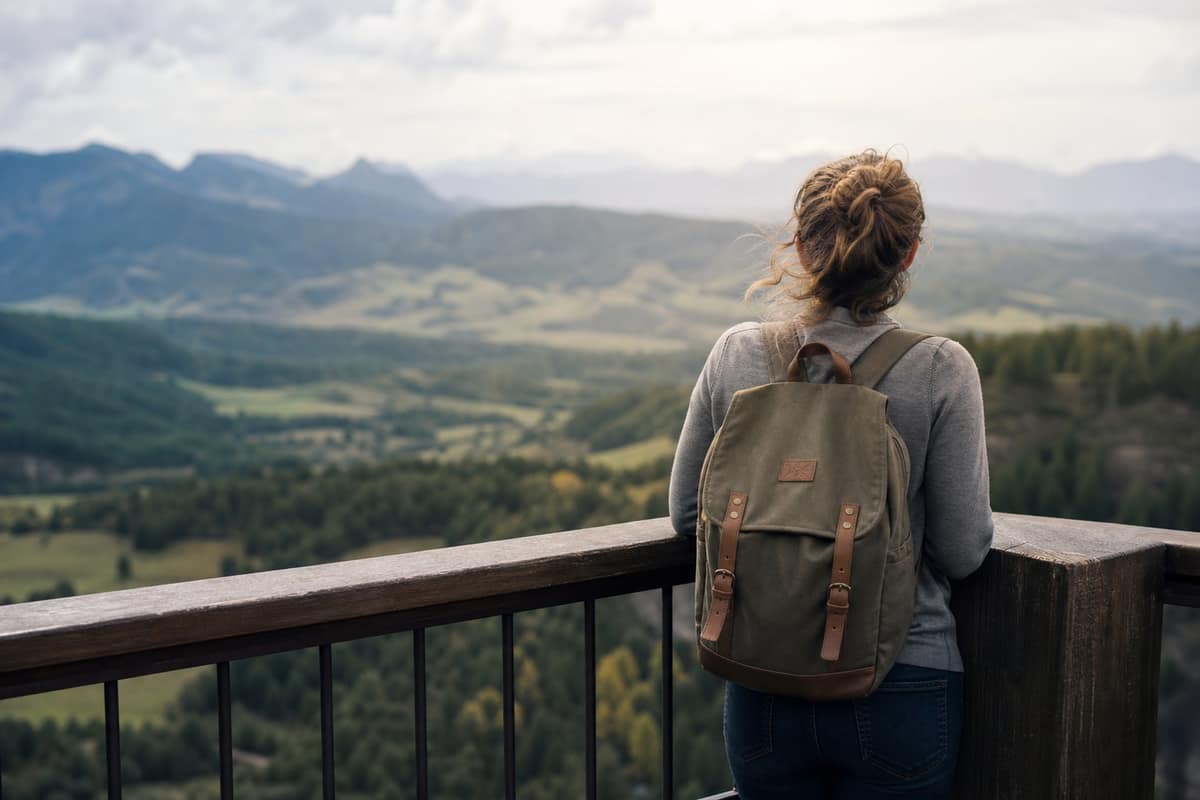 Personne accoudée à une rambarde qui observe un paysage en contrebas