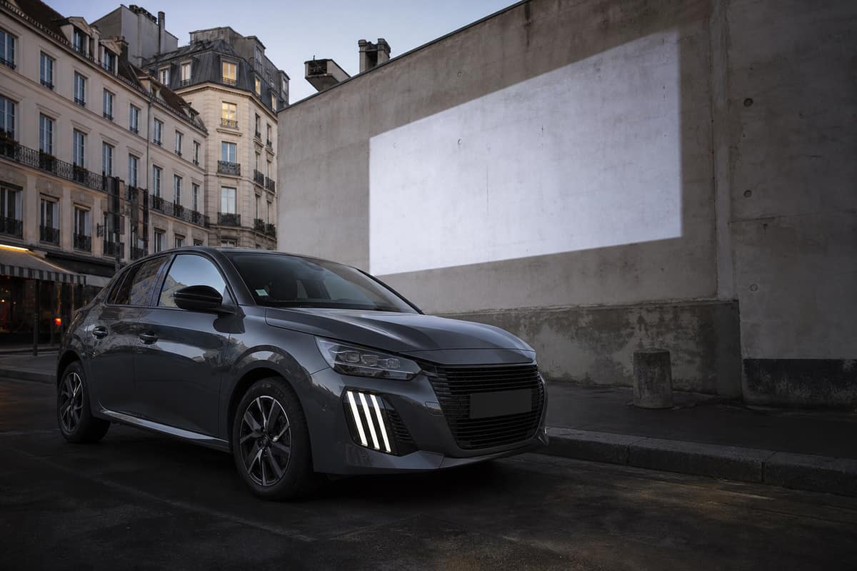 Voiture compacte moderne devant une projection lumineuse sur un mur urbain français