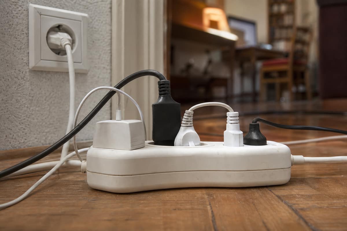 Multiprise électrique avec plusieurs appareils branchés au sol d’un salon