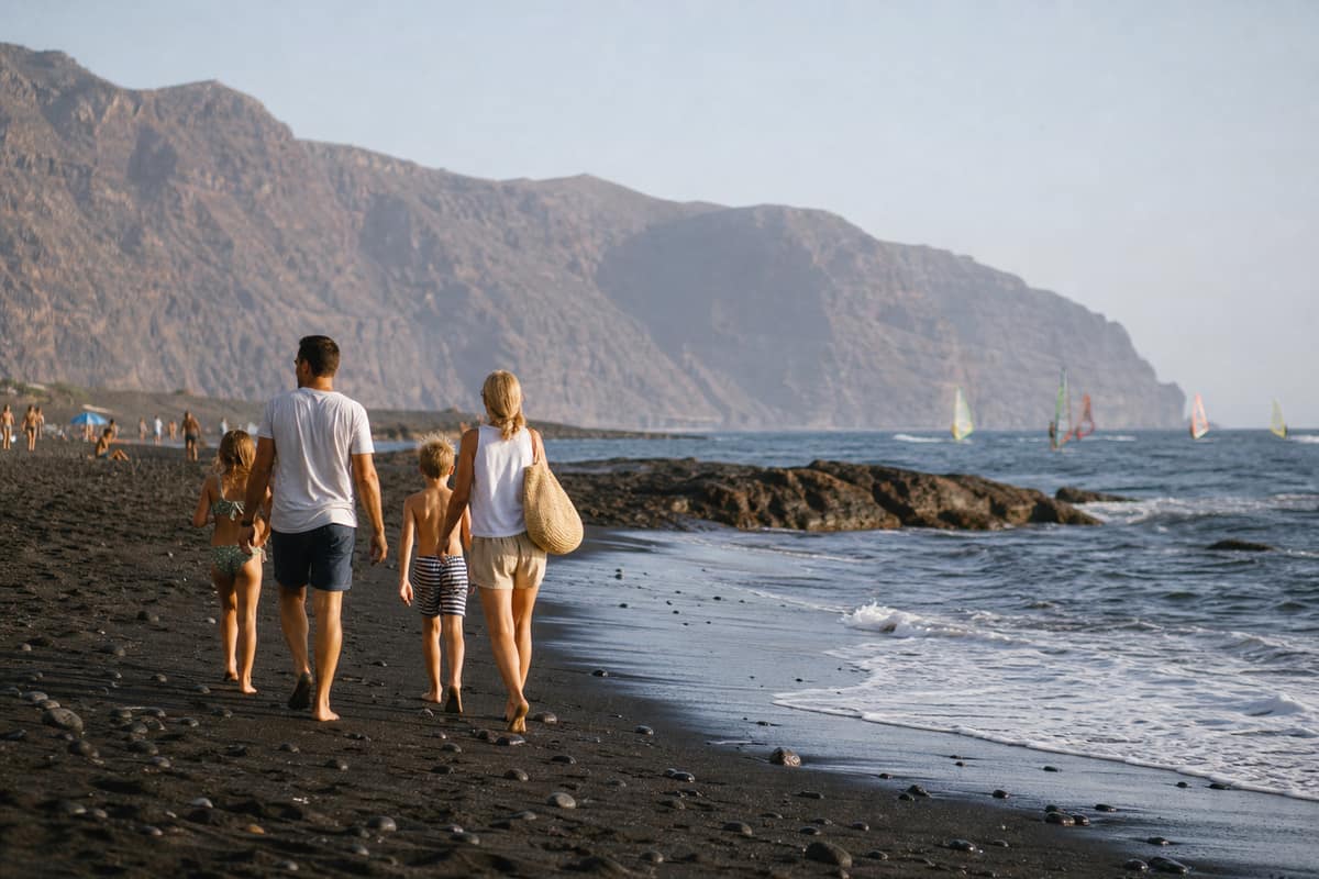 Plage volcanique de Tenerife avec falaises atlantiques et voiles de windsurf au loin