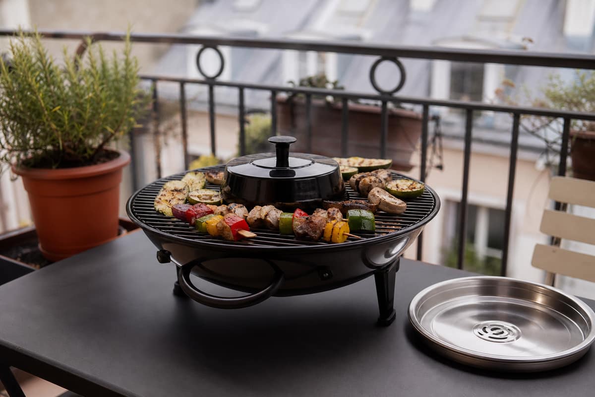 Petit barbecue à charbon à fumée réduite sur une terrasse avec légumes grillés