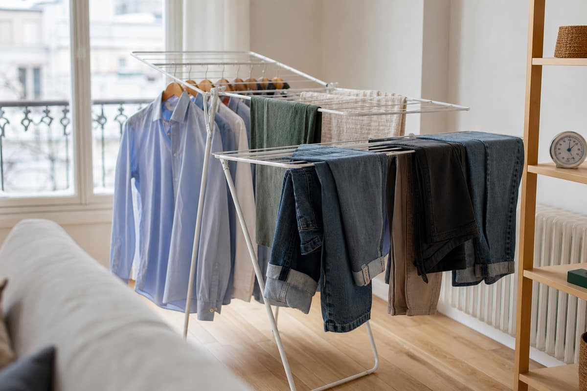 Étendoir aéré avec vêtements, serviettes et jeans dans un salon lumineux en hiver