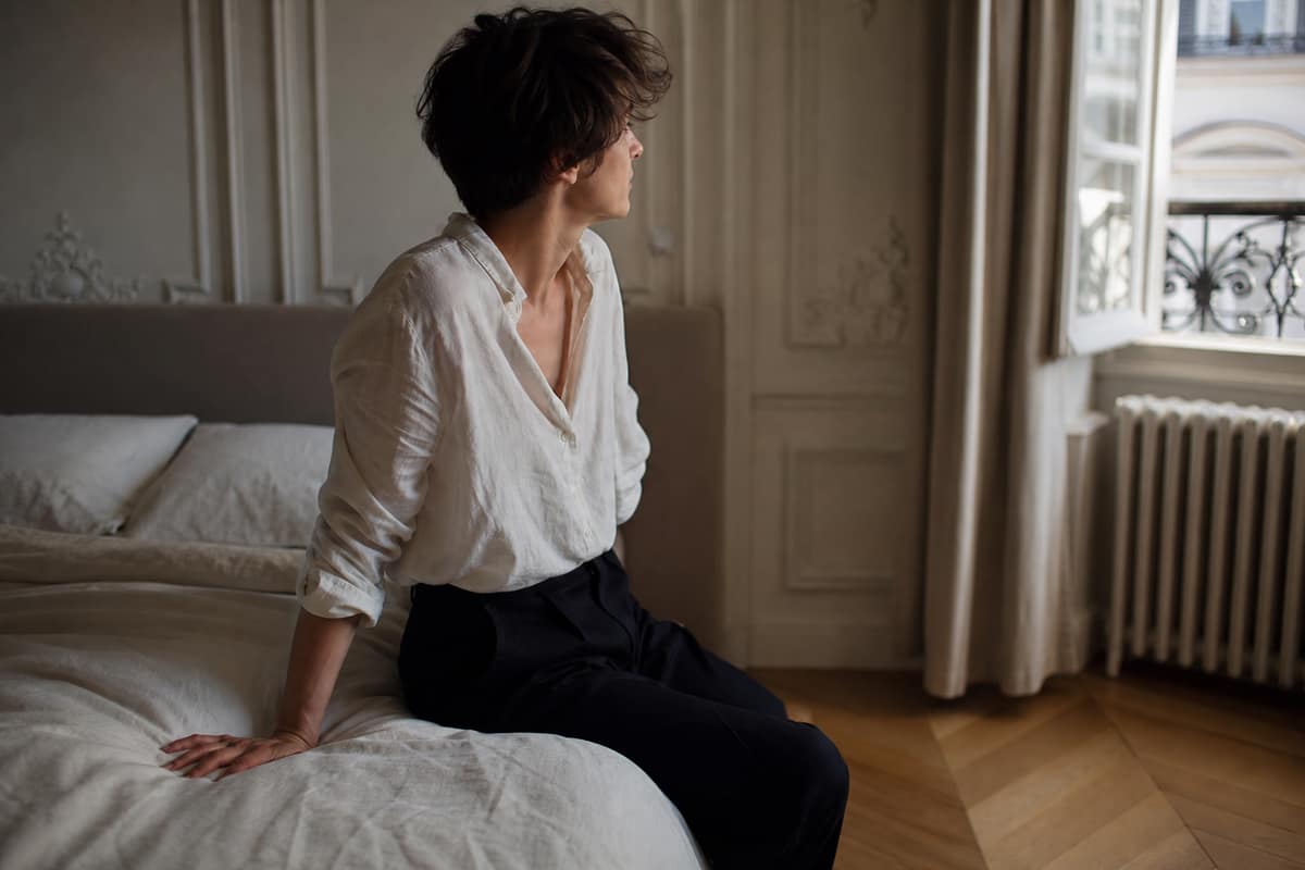 Personne assise au bord du lit au réveil, marquant une pause avant de se lever